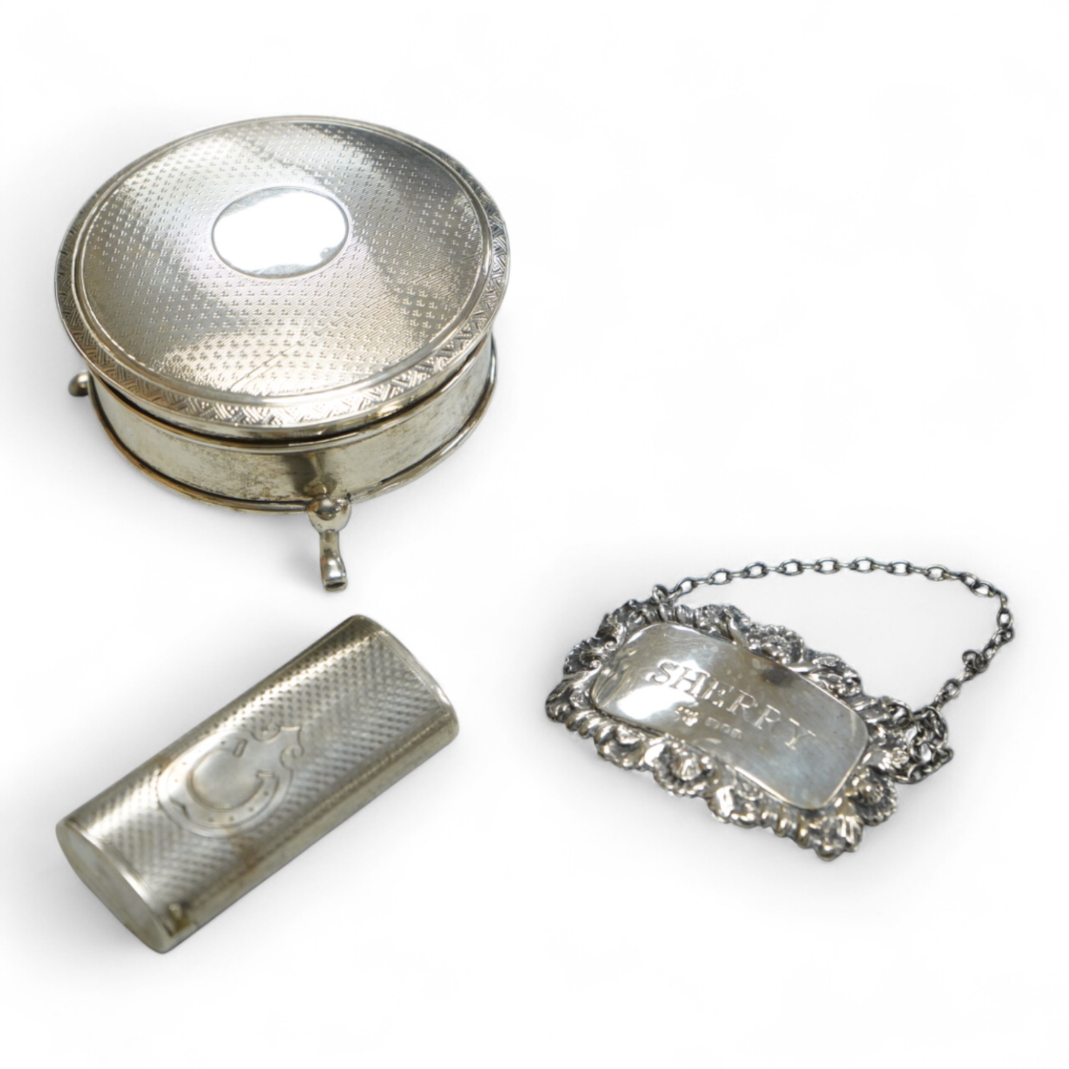 A George V silver mounted circular trinket box by Horton & Allday, Birmingham, 1916, diameter 75mm, together with a 19th century German? white metal vesta case and a modern silver wine label.